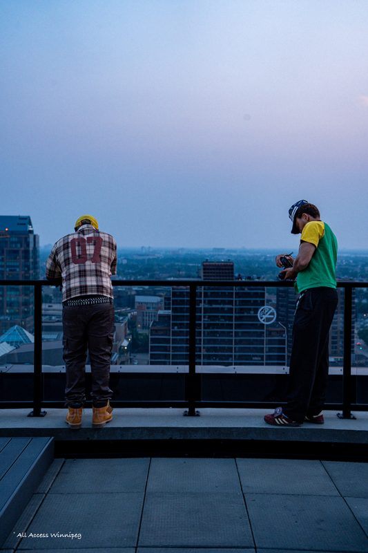 Two artists at the rooftop railing at dusk, Konfam shoot, Winnipeg