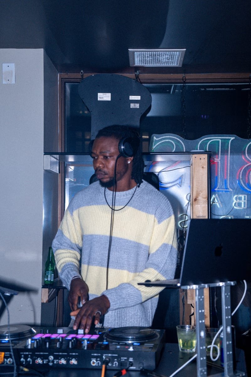 DJ in a striped sweater and headphones mixing at the decks