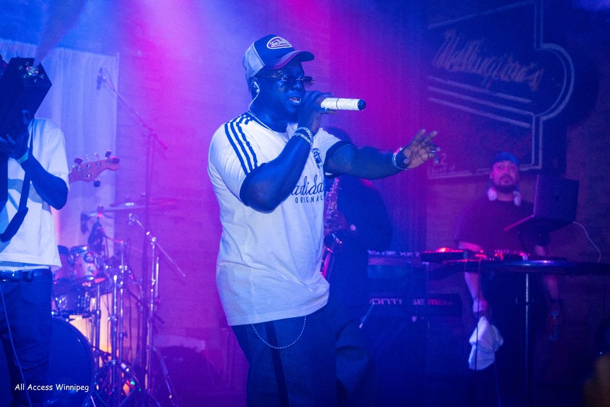 Performer on the mic on stage under purple light, live band behind