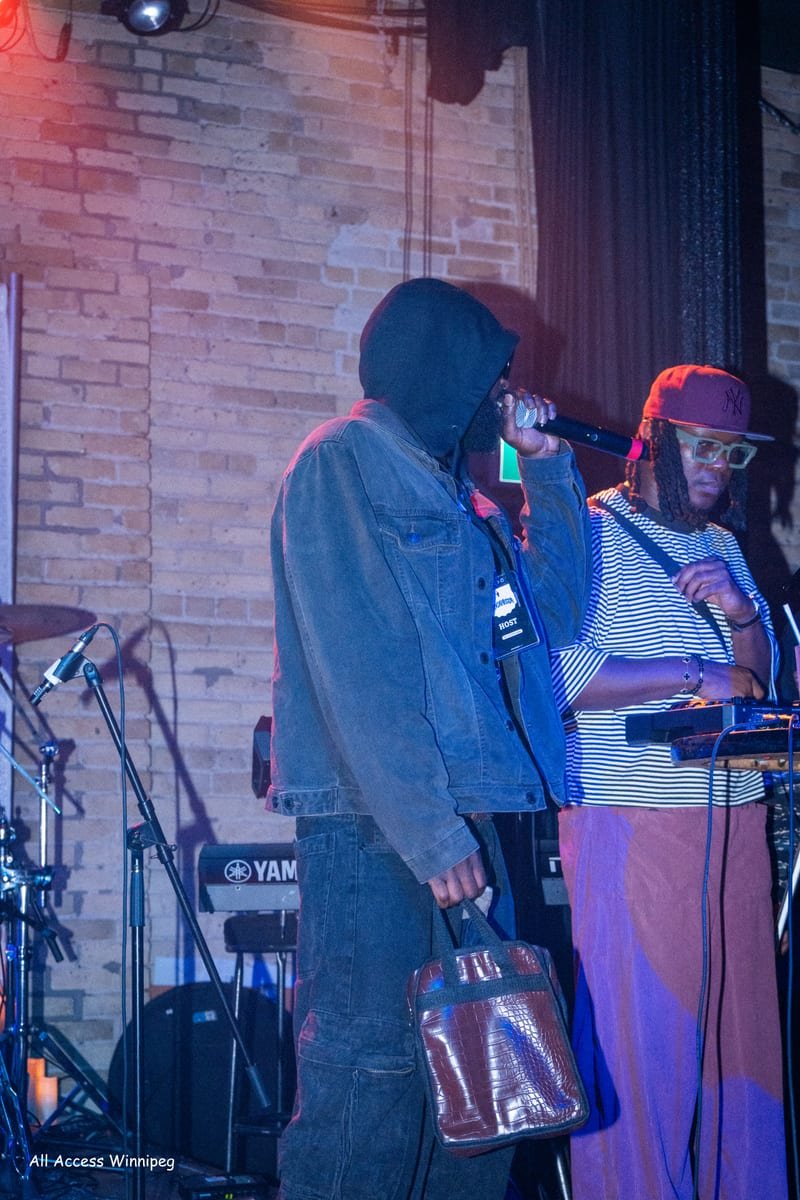 Wide shot of the stage — performer, DJ and keys under low light