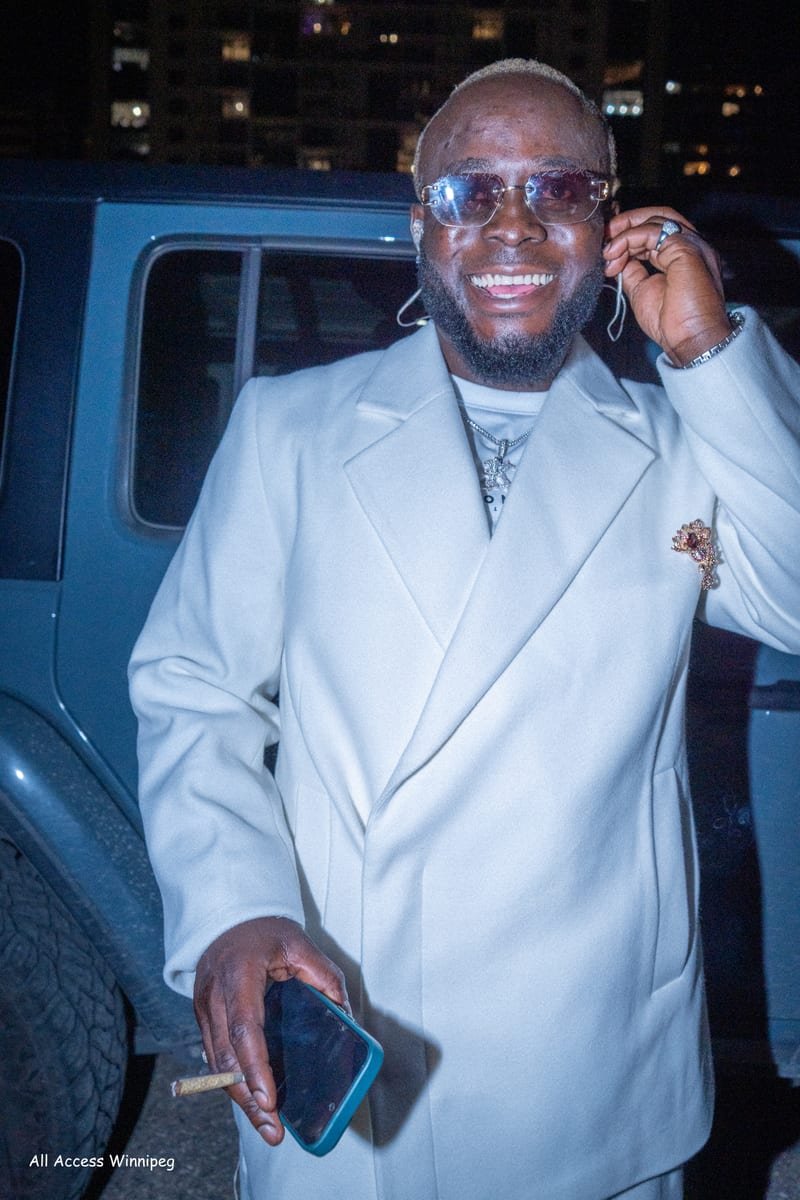 Guest in a white suit smiling on the street at night