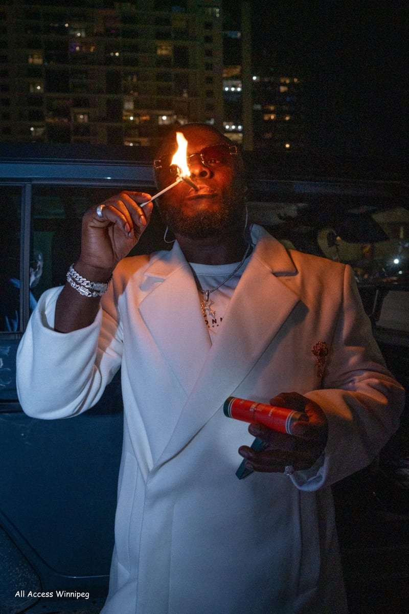 Guest in a white suit lighting up, city lights behind