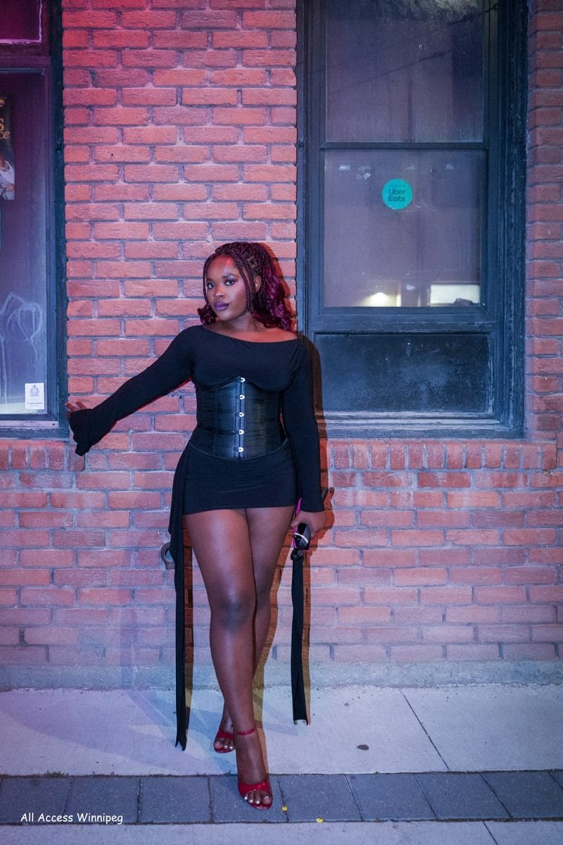 Guest in a black dress posed against the venue wall