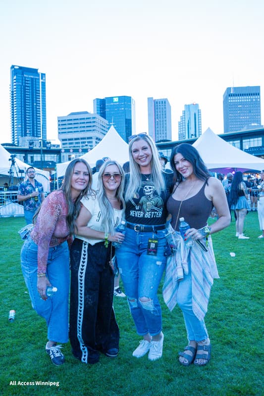 Group of friends posed together with the Winnipeg skyline at sunset