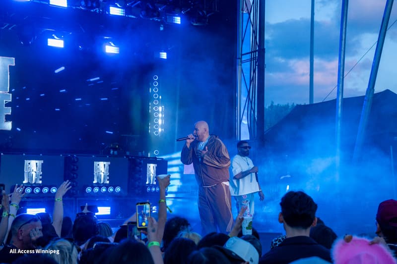 Fat Joe performing under blue stage lighting, crowd holding up phones