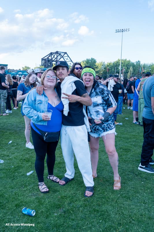 Four friends posed together with the Winnipeg skyline behind them