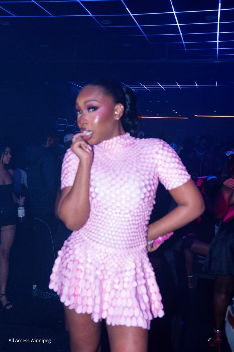 Guest in a pink sculpted dress with a hand to her mouth under the laser ceiling