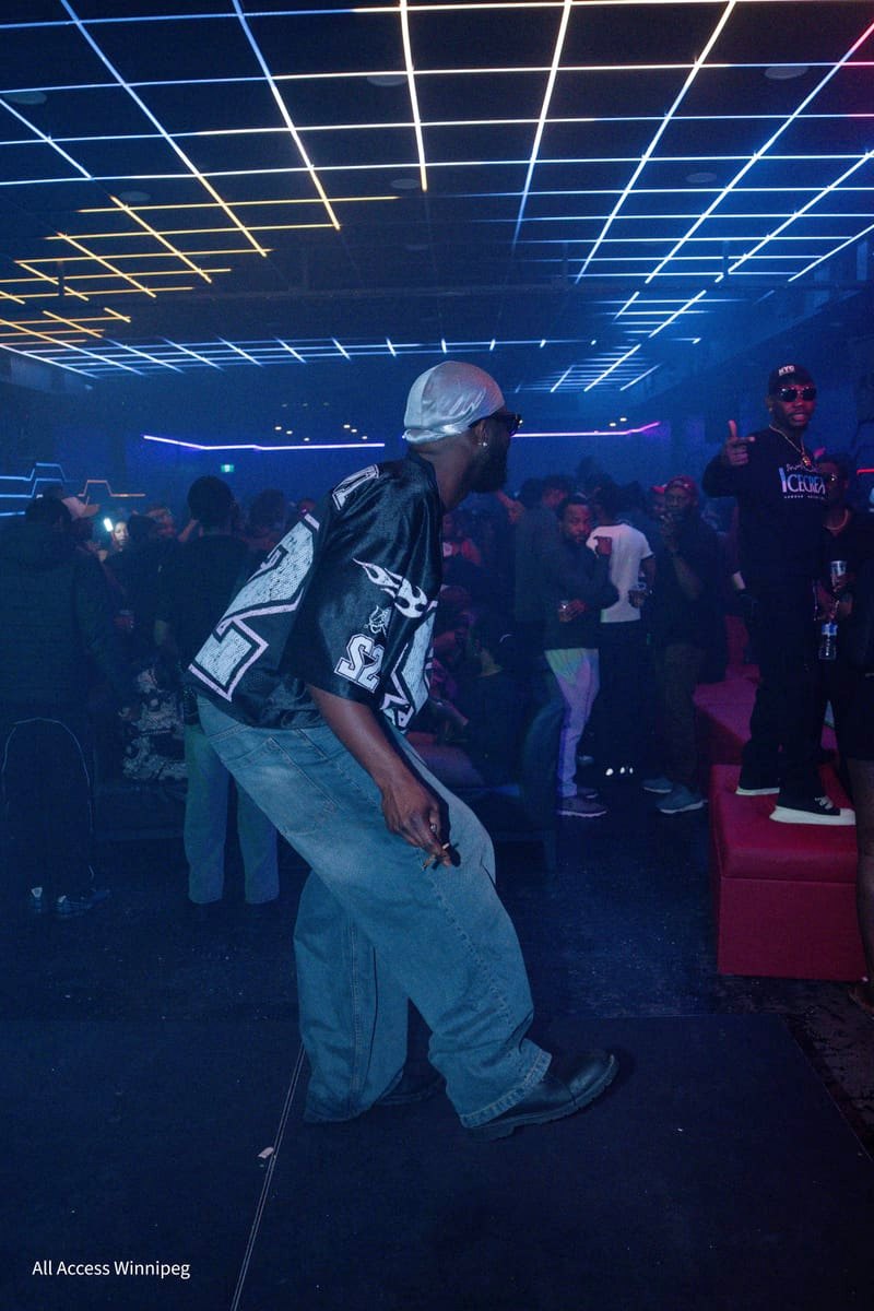 Guest in a flame-print jersey dancing as the crowd fills the floor under the laser ceiling